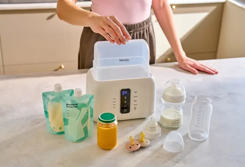 Pudelīšu sildītājs Lionelo Thermup Duo virtuvē uz galda ar dažādiem priekšmetiem